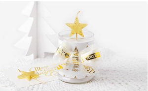 Dettaglio candela di Natale con nastro dorato Merry Christmas e stecchi a stella