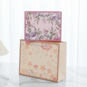 Detail of vintage floral paper gift bags with blue braided handles and elegant prints