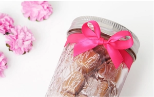 Detailed view of neon pink polyester ribbon tied in a bow on a glass candy jar