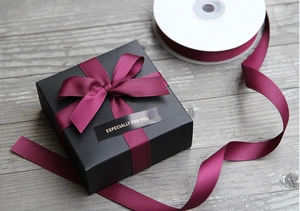 Close-up of black gift box with burgundy grosgrain ribbon and especially for you tag