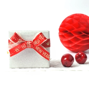 Glittery silver gift box with red Happy New Year ribbon and festive silk bow detail
