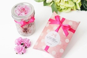 Pink ribbon bow on textured glass jar and polka dot gift box for first birthday party