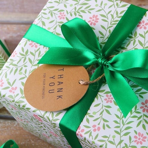 Green satin ribbon and white floral gift wrap with kraft paper thank you tag