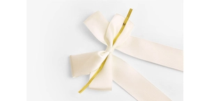 Detail of cream satin bows with gold twist ties for gift wrapping and bakery packaging