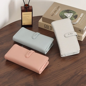 Detailed view of leather texture and strap snap on pink, blue, and white long wallets