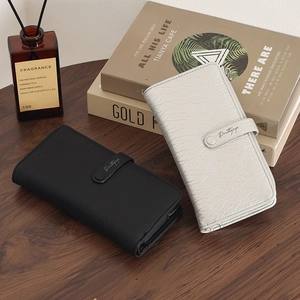 Close-up of black and beige long wallets with litchi texture and metal snap closure