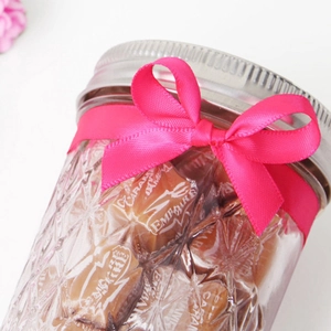 Neon pink polyester ribbon tied in a bow on a glass jar with embossed diamond pattern