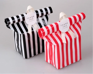 Close-up of striped gift bags with ribbons and Thank You stickers for cookies