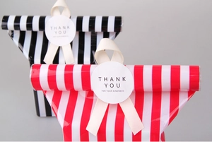 Detail of red and black striped gift bags with cream ribbons and thank you stickers