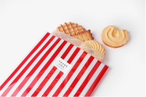 Detail of red striped food packaging bag with Thank You sealing sticker and cookies