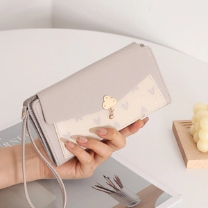 Détail du portefeuille long avec imprimé cœur et boucle nuage dorée avec dragonne assortie