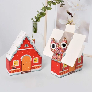 Creative red house-shaped gift box with snowy patterns and a floral cat plush inside