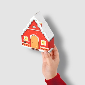 Miniature house-shaped red gift box with white snowy roof and gold polka dots pattern
