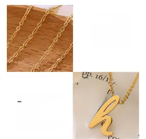 Détail macro du pendentif lettre H plaqué or 18K et texture de chaîne en titane