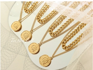 Detail of double-layer gold plated portrait coin necklace on a mirror background