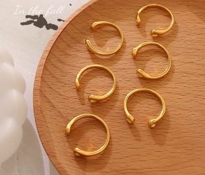 Set of 6 minimalist gold teardrop open rings displayed on a rustic wooden tray