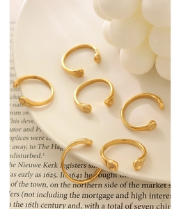 Detail view of 18K gold plated minimalist C-shaped open rings on vintage books