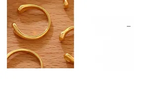 Detail of 18K gold-plated minimalist rings with glossy liquid droplet design on wood