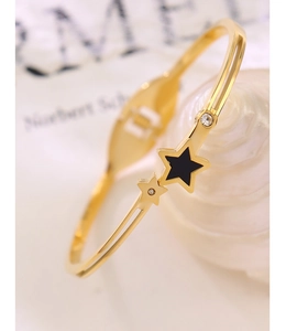 Macro detail of gold star bracelet featuring black enamel and sparkling rhinestones