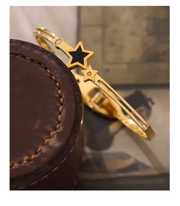 Detail of star-shaped gold bracelet with black enamel inlay and sparkling crystals