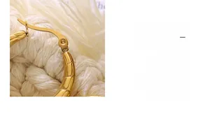 Vista macro dettagliata degli orecchini a U placcati oro 18K con trama geometrica
