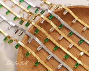Détail de la chaîne serpent dorée avec des zircons verts émeraude de coupe baguette
