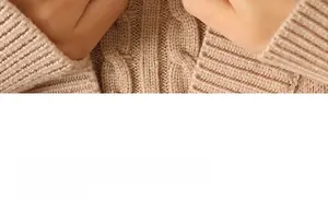 Vue macro de la maille torsadée d'un pull en laine beige montrant les détails du col
