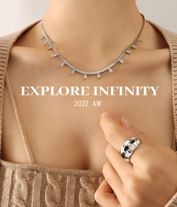 Détail du collier à chaîne serpent argentée avec zircons sur un pull en maille beige