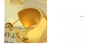 Gros plan de boucles d'oreilles dorées en forme de C avec une finition miroir lisse et élégante