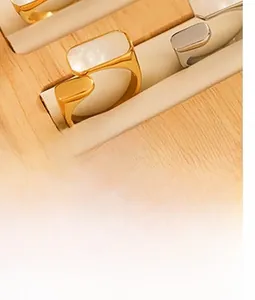 Détail de bagues géométriques dorées avec incrustation en nacre sur plateau à bijoux