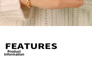 Détail d'un bracelet fleuri doré ajouré porté sur une manche en maille blanche