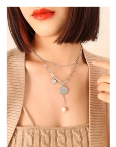 Détail d'un collier argenté multicouche avec médaille portrait et perle élégante