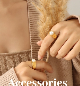 Detail of 18K gold-plated wide band rings with inlaid white pearls on knit sweater