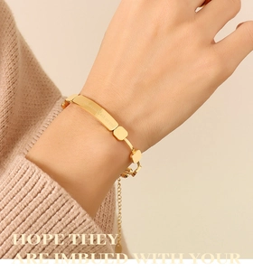 Detail of 18K gold plated bracelet showing engraved nameplate and square link chain on wrist