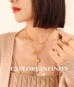 Détail du collier doré multicouche avec médaille portrait, perle et bagues vintage