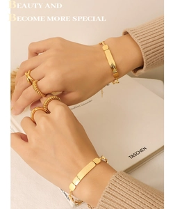 Detail view of 18K gold plated bracelet and rings set with engraved metal plates