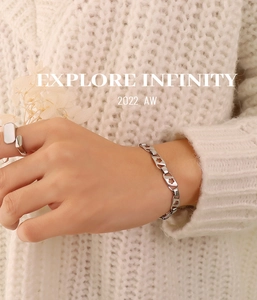 Gros plan sur un bracelet à fleurs ajourées et une bague portés sur un pull beige
