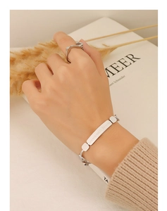 Detail of silver stainless steel engraved bracelet and unique hook ring on model's hand