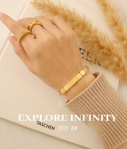 Close-up of a gold jewelry set with an engraved plaque bracelet and two minimalist rings