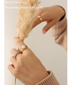 Close-up of gold plated rings with white pearls and black and white checkered enamel
