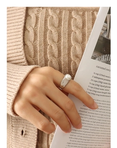Detail of a vintage-style pearl ring in silver finish worn with a cozy knit sweater