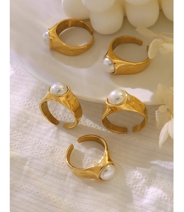 Detailed view of five vintage gold rings with pearls on white ceramic and floral background