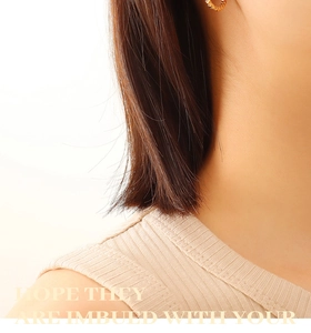 Gros plan de boucles d'oreilles créoles torsadées dorées portées pour un style minimaliste