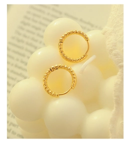 Détail de boucles d'oreilles créoles plaquées or 18K avec finition ciselée texturée