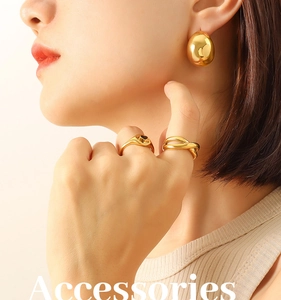 Close-up of a model wearing hollow C-shaped gold earrings and minimalist rings