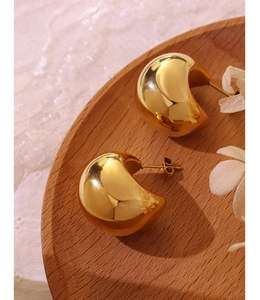 Detail of 18K gold-plated hollow C-shaped hoop earrings on a vintage lace background