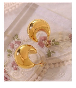 Close-up of polished 18K gold plated hollow C-shaped hoop earrings on vintage lace