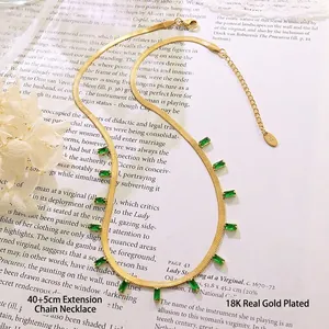 Collier maille serpent plaqué or 18K avec pendentifs zircon vert sur un livre d'art