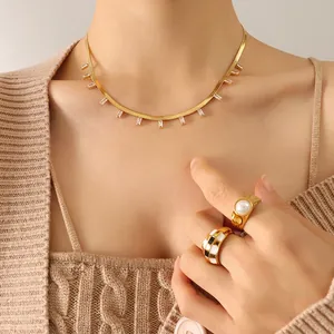 Collier chaîne serpent dorée avec pendentifs en zircone rectangulaires sur un pull