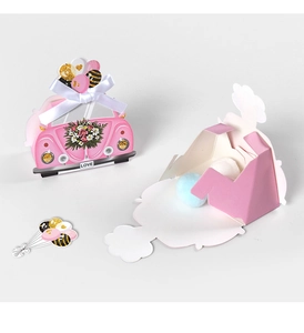 Detail van roze papieren bedankdoosjes in autovorm met zijden linten en kleurrijke snoepjes